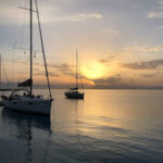 Skippertraining Korfu Segeln zwei Segelyachten ankern vor Voutoumi bei malerischen Sonnenaufgang