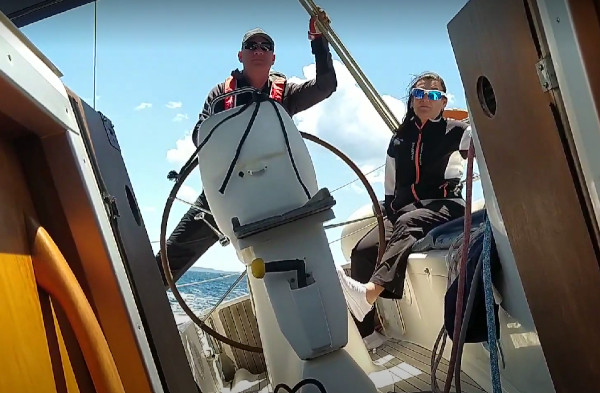 Paar Skippertraining von Korfu Segeln für Paare, Seglerpaar am Steuerstand einer Segelyacht am Wind mit Kränkung