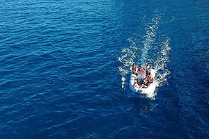 Schlauchboot mit Crew in voller Fahrt auf blauem Wasser